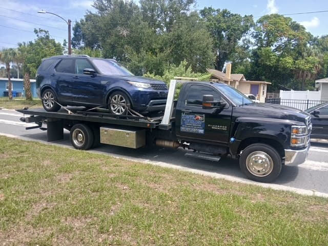 Dark blue Land Rover Discovery loaded on the flatbed on a residential street