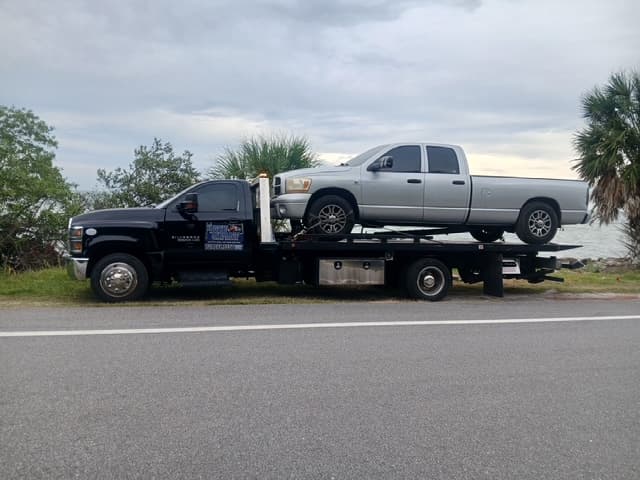 Silver Ram quad cab pickup on the flatbed along the waterfront