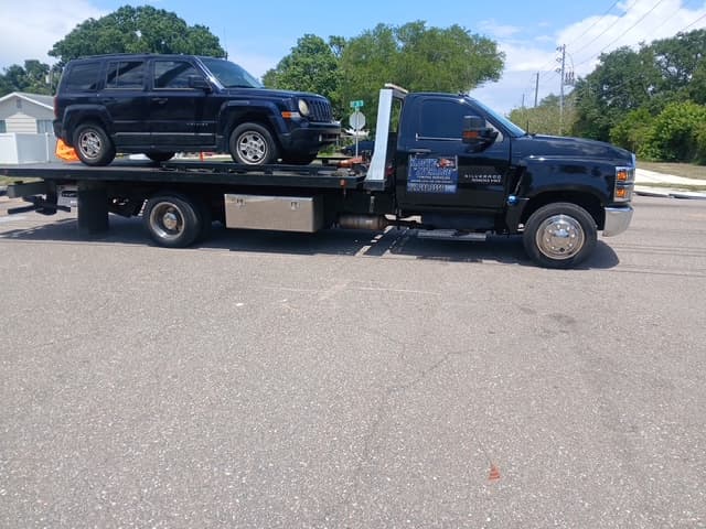 Black Jeep Patriot on the flatbed at a neighborhood intersection