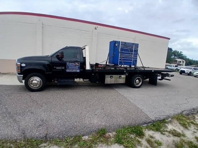 Large blue rolling tool cabinet strapped to the flatbed outside a shop