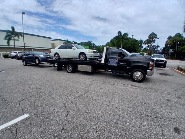 White Lexus sedan on the flatbed with a second vehicle towed on the wheel lift